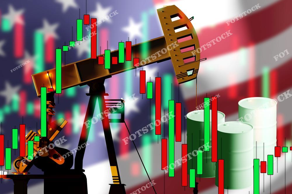 На изображении показана нефтяная качалка с капающей нефтью, рядом с которой расположены бочки. На заднем плане виден размытый американский флаг и биржевые графики, символизирующие влияние цен на нефть на экономику. Фотография объединяет энергетику и мировые финансовые процессы.